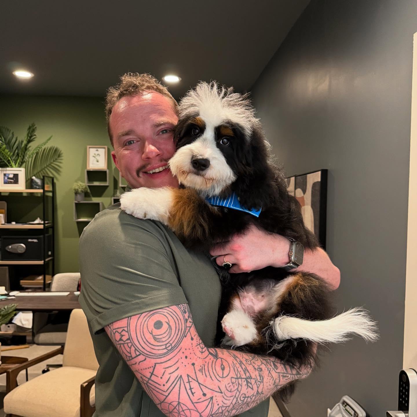 A smiling Tino’s team member holding a fluffy tricolor dog in the salon