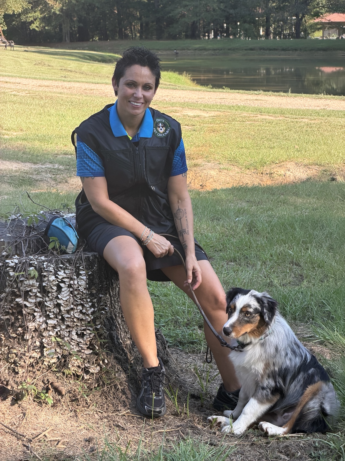 Nikki Ray seated outdoors beside a blue merle Australian Shepherd